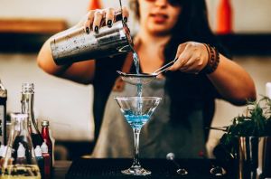 Barkeeperin beim abseihen eines Aviation Gin Cocktails