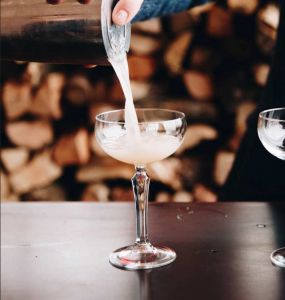 Last Word Cocktail der aus einem Shaker in eine Cocktailschale abgeseiht wird