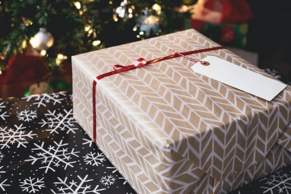 Eingepacktes Weihnachtsgeschenk mit hellem Papier und roter Schleife
