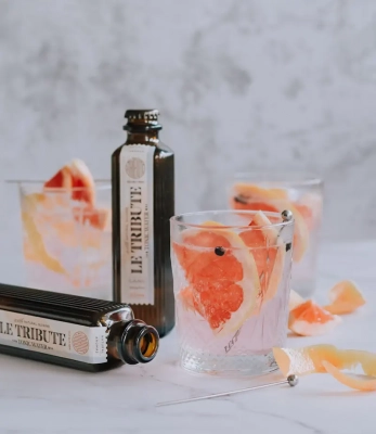Le Tribute Tonic Flaschen mit einem Gin Tonic garniert mit Grapefruits